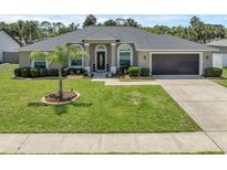 Charming single Gathering home featuring a well-manicured lawn, elegant landscaping, and an attached two-car garage at 445 Oakland Park Blvd, Port Orange, FL 32127