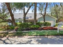 Charming single-story home featuring light-blue siding, mature trees, and lush landscaping at 8554 Amber Oak Dr, Orlando, FL 32817