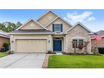 Charming single-Gathering home featuring stone accents, a blue front door, and a well-maintained lawn at 11225 Cypress Trail Dr, Orlando, FL 32825