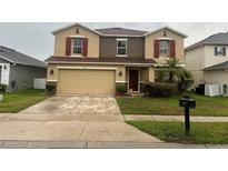 Two-story home featuring a two-car garage, red shutters, and a well-maintained front lawn at 1325 Bella Coola Dr, Orlando, FL 32828