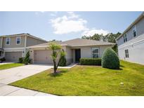 Well-maintained single-story home with a manicured lawn, decorative shrubbery, and attached two-car garage at 13851 Rushing Creek Run, Orlando, FL 32824