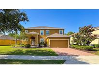 Charming two-story home with a well-manicured lawn and inviting brick driveway at 206 Yellow Snapdragon Dr, Davenport, FL 33837