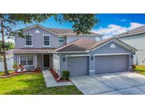 Charming gray two-story home with a three-car garage and a well-manicured lawn at 3234 Amberley Park Cir, Kissimmee, FL 34743