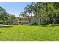 Charming two-story home with a sprawling green lawn and mature landscaping, including palm trees at 33925 Highland Rd, Leesburg, FL 34788