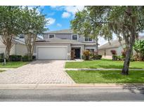 Charming two-story home features a brick driveway, two-car garage, and manicured lawn at 4785 Cumbrian Lakes Dr, Kissimmee, FL 34746