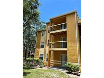 A three-story condo building with balconies, mature trees and nice landscaping at 5291 Images Cir # 301, Kissimmee, FL 34746