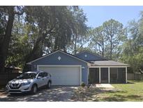 Charming blue single-story home with a two-car garage and a screened-in front porch at 6436 Fig Leaf St, Magnolia Square, FL 34771
