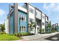 Modern townhouse exterior featuring blue and gray siding with large windows and manicured landscaping at 7770 Sandy Ridge Dr # 234, Reunion, FL 34747