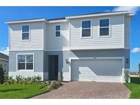 Two-story home with a two-car garage, red brick driveway, and manicured landscaping at 7779 Trapani Loop, Clermont, FL 34714