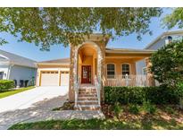 Inviting tan home with a striking arched entrance, two-car garage, and a cozy porch with white railing at 10076 Kimble Field Way, Orlando, FL 32827