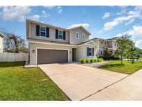 Two-story home featuring a gray exterior, well-manicured lawn, and attached two-car garage at 1073 River Otter Way, Deland, FL 32720