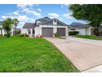 Charming home featuring a well-manicured lawn and a two-car garage with a classic design, creating curb appeal at 109 Lakepointe Cir, Kissimmee, FL 34743