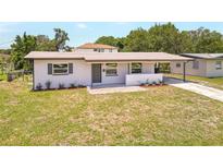 Exterior shot of home with front lawn, covered porch, updated facade, landscaping, and driveway at 1118 Roberta Ave, Orlando, FL 32825