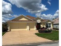 Charming home with a three-car garage, well-manicured lawn and a beautifully patterned driveway at 1121 Alcove Loop, The Villages, FL 32162
