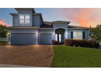 Charming two-story home featuring a three-car garage, brick driveway, manicured lawn, and arched entryway at 1265 Blarney St, Minneola, FL 34715