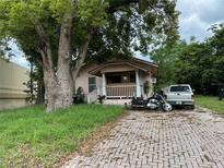 Charming home featuring a cozy porch, brick driveway, and mature trees enhancing curb appeal at 1996 Indiana Ave, Winter Park, FL 32789