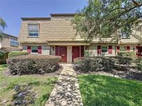 Inviting townhouse with a brick facade, red door and shutters, and well-maintained landscaping at 200 Saint Andrews Blvd # 3002, Winter Park, FL 32792