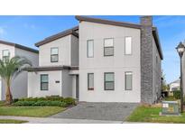 Modern two-story home with a stone chimney, paver driveway, and manicured landscaping at 2927 Fable St, Kissimmee, FL 34746