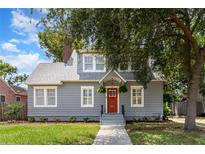 Charming gray home featuring a red door, manicured lawn, and mature trees enhancing curb appeal at 338 E Anderson St, Orlando, FL 32801