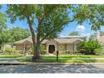 Charming single-story home boasts mature landscaping and a well-manicured lawn under a blue sky at 7699 Milano Dr, Orlando, FL 32835