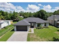 A charming single-story home featuring a manicured lawn, grey brick driveway, and dark grey trim at 934 Jessamy St, Oviedo, FL 32765