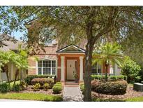 Charming two-story home featuring a welcoming front porch, manicured landscaping, and a brick walkway at 14781 Old Thicket Trce, Winter Garden, FL 34787