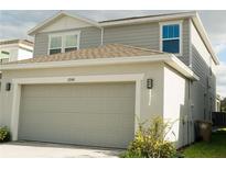 Two-story home with a gray exterior, a two-car garage, and well maintained landscaping at 17148 Cagan Crossings Blvd, Clermont, FL 34714