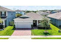 Charming single Gathering home featuring a two car garage and brick paved driveway at 2223 Blue Salvia St, Clermont, FL 34711