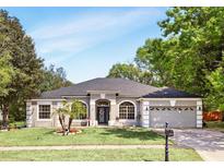 Charming single-story home with a manicured lawn, arched windows, and a two-car garage at 3451 Players Point Loop, Apopka, FL 32712