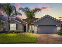 Charming single-story home with a two-car garage, beautiful landscaping, and tropical palm trees against a colorful sunset backdrop at 3925 Green Sabal Dr, Orlando, FL 32824
