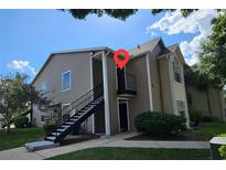 Two-story condo with tan siding, black stairs, second story balcony, and landscaping at 4704 Walden Cir # 21, Orlando, FL 32811