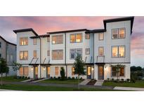 Modern townhome with a charming exterior, beautiful landscaping, and a well-lit entryway creating a welcoming ambiance at 8460 Sperry St, Orlando, FL 32827