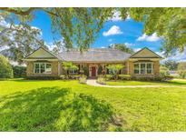 Charming brick home featuring manicured lawn, mature trees, and a welcoming red front door at 8812 S Bay Dr, Orlando, FL 32819