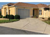 Charming single-story home with tan exterior, landscaped front yard, and well-lit driveway at 1221 Santa Cruz Dr, The Villages, FL 32162