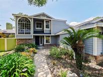 Charming two-story home with blue siding, a beautifully landscaped front yard, and a welcoming walkway to the front door at 208 Frinton Cv, Longwood, FL 32779
