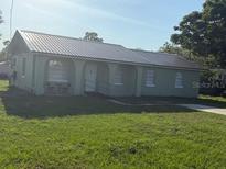 Quaint single-story home featuring a modern metal roof, arched front entry and well-maintained lawn at 410 5Th S St, Dundee, FL 33838