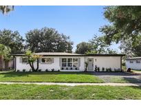 Charming single-story home with white exterior, gray shutters, complemented by a green lawn and mature landscaping at 606 Faber Dr, Orlando, FL 32822