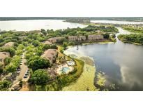 Stunning aerial view of the community featuring lush greenery, a shimmering lake, and a sparkling swimming pool at 8801 Latrec Ave # 8101, Orlando, FL 32819