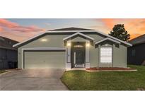 Charming single-story home with a well-manicured lawn and a two-car garage at sunset at 1111 High Vista Dr, Davenport, FL 33837