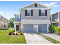 Charming two-story home with gray siding, two-car garage, and meticulously landscaped front yard at 1396 Mirabella Cir, Davenport, FL 33897