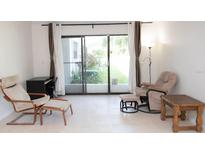 Bright living room featuring neutral tile flooring and large sliding glass doors to the outside at 1504 Virginia Ave # 105, Daytona Beach, FL 32114