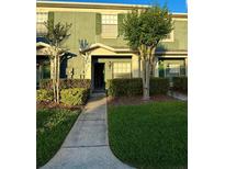 Inviting townhouse with a well-maintained lawn, lush shrubbery, and a sidewalk leading to the front door at 3549 Wilshire Way Rd # 56, Orlando, FL 32829