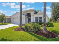 Inviting single-story home featuring a manicured lawn, mature landscaping, and a two-car garage at 5560 Squires Dr, Leesburg, FL 34748