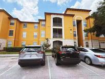 Attractive yellow apartment building with three parked cars and manicured landscaping at 6169 Metrowest Blvd # 308, Orlando, FL 32835