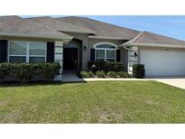 Charming single-story home with a well-manicured lawn and inviting curb appeal, complemented by lush landscaping at 6800 Se 12Th Pl, Ocala, FL 34472