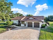 Charming stucco home featuring a terra cotta tile roof, a two-car garage, and a beautiful brick driveway at 6969 Edgeworth Dr, Orlando, FL 32819