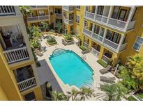 Aerial view of a community swimming pool with lounge chairs and well-maintained landscaping between yellow buildings at 860 N Orange Ave # 448, Orlando, FL 32801
