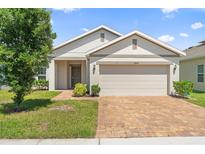 Charming single-story home featuring a brick driveway, a two-car garage, and a neatly maintained lawn at 9356 St Therese St, Groveland, FL 34736