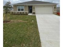Charming single-story home with well-maintained lawn and a two car garage on a cloudy day at 1575 Aspen Ave, Davenport, FL 33837