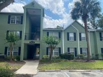 Condo building with green exterior, black shutters, and tropical landscaping at 2007 Dixie Belle Dr # 2007 M, Orlando, FL 32812